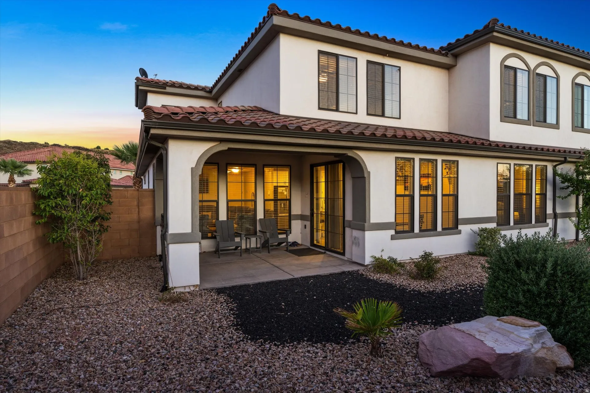 Stucco exterior with a tiled roof and multiple large windows
