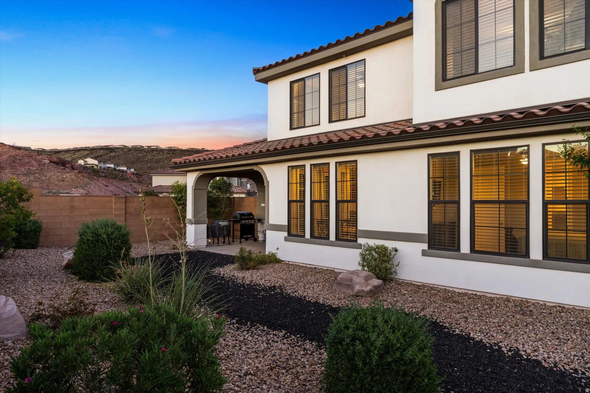 Stucco exterior with a tile roof, an arched covered patio, and multi-pane windows