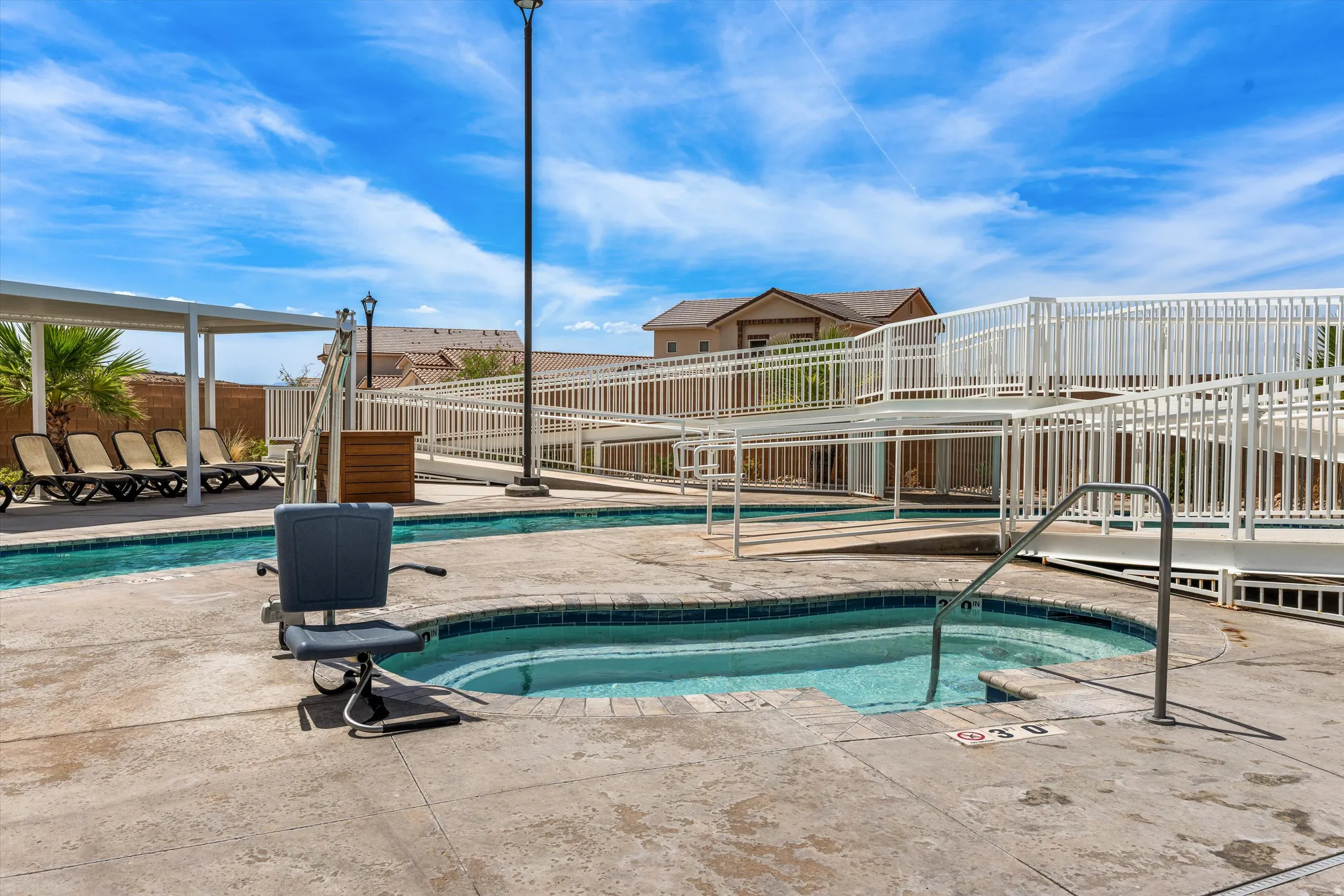 Shallow-entry pool with integrated spa, concrete deck, and shaded lounge area