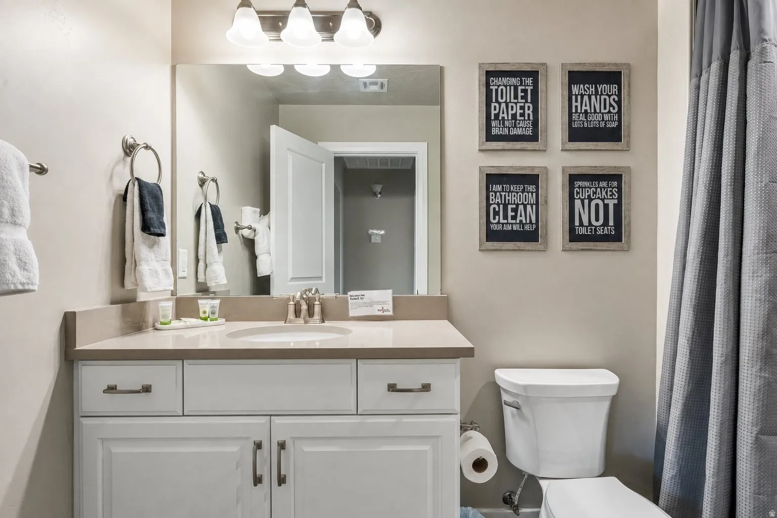 Vanity with an integrated sink, brushed nickel fixtures, a framed mirror, and a wall-mounted light fixture