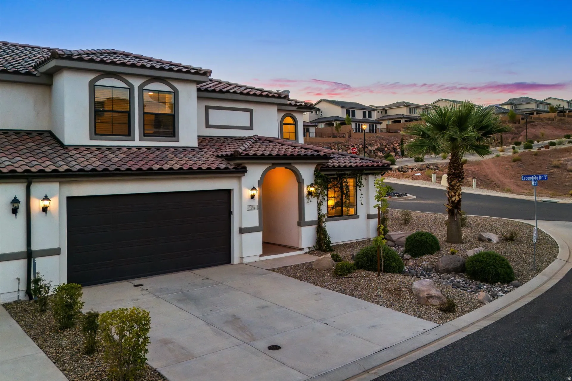 Stucco exterior with a tiled roof, arched windows, and an attached garage