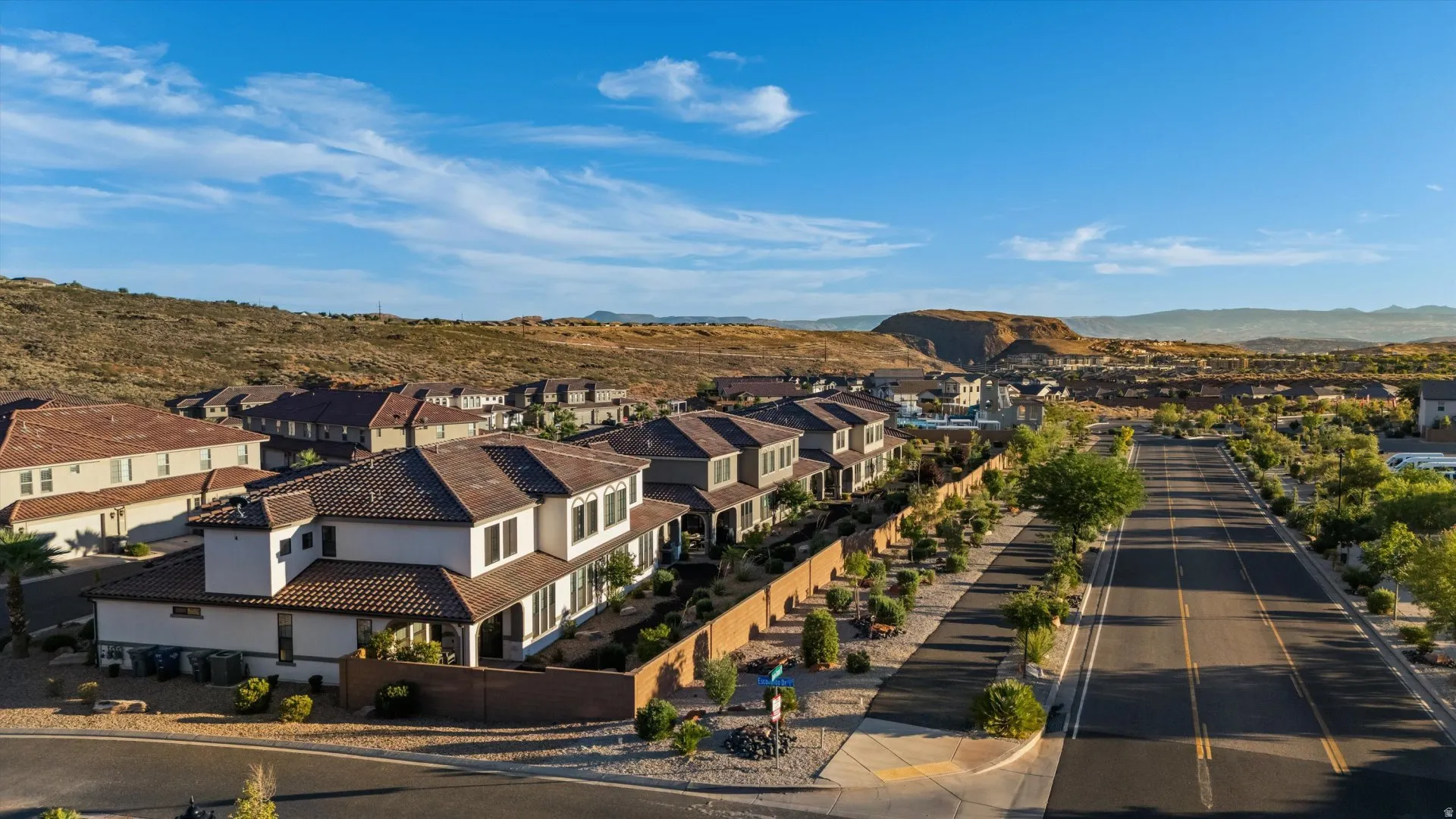 Residential community featuring tile-roofed homes, paved streets, and extensive landscaping with desert plantings