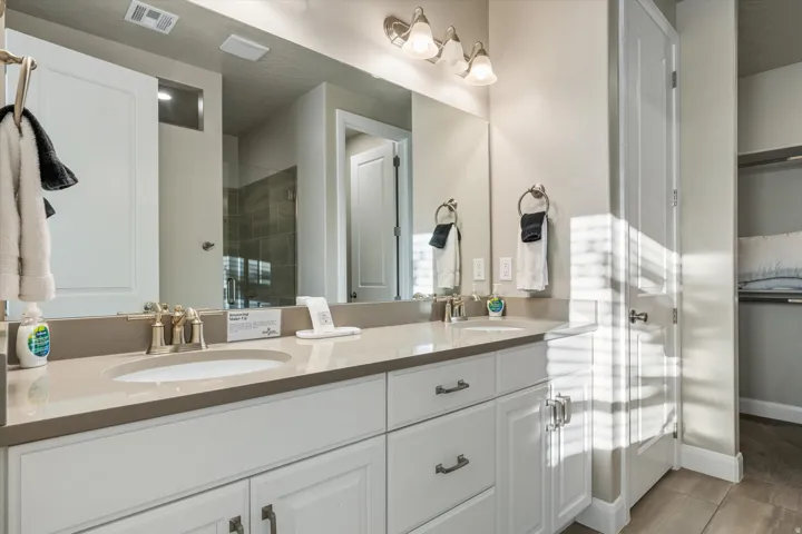 Double vanity with integrated sinks, light-toned countertop, white cabinetry with dark hardware, and brushed nickel fixtures