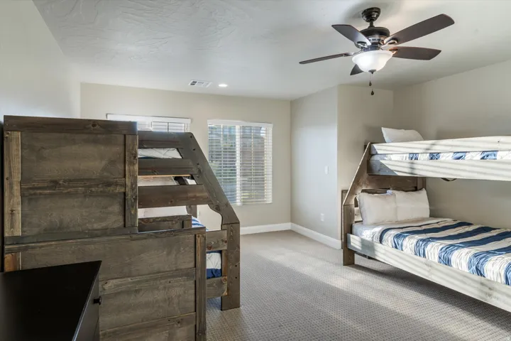 Carpeted room featuring bunk beds, a ceiling fan, and window blinds