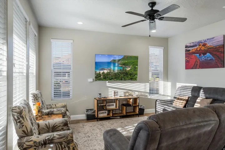 Recessed lighting, wood-finish flooring, ceiling fan, multiple windows with blinds, and a built-in wall-mounted television