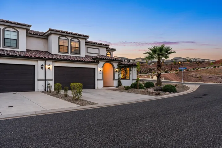 Stucco exterior with arched entry, two garages, tile roofing, and arched windows