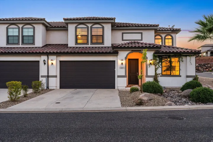 Stucco exterior with a tile roof, arched windows, an arched entryway, and a two-car garage