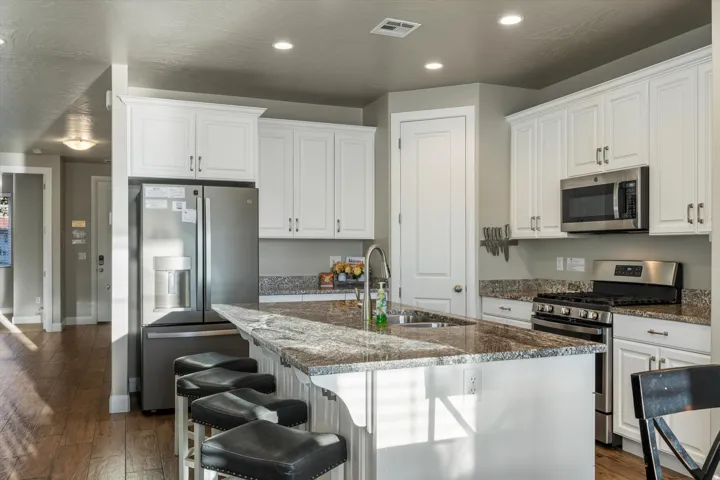 Kitchen featuring white cabinetry, stainless steel appliances, a multi-tonal countertop, and wood-finish flooring