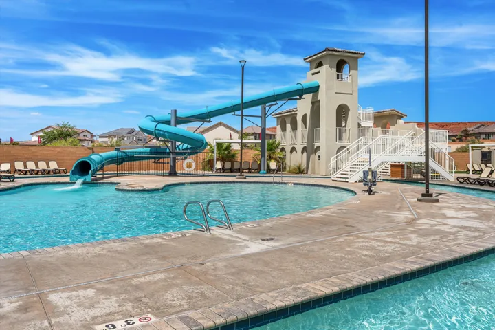 Resort-style pool with a water slide, integrated pool stairs, and a surrounding concrete deck
