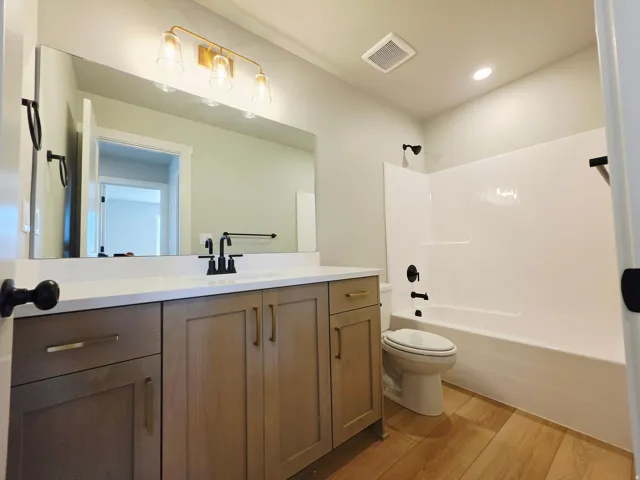 Vanity with a solid surface countertop, matte black faucet, and wood-finish cabinetry