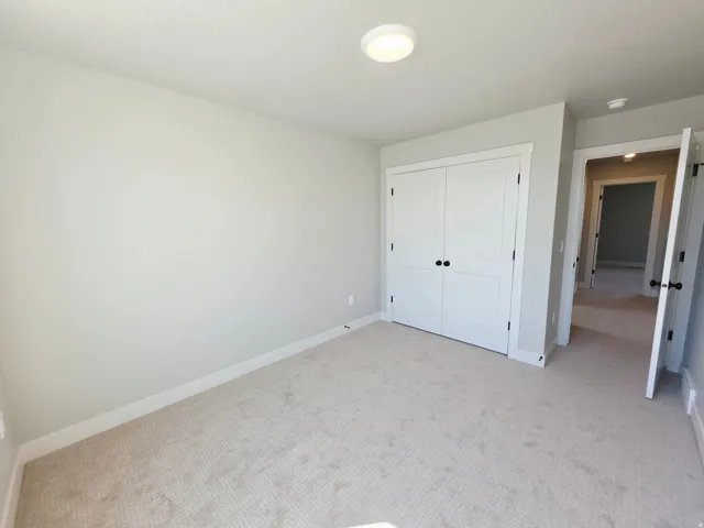 Neutral-toned carpeting, white bi-fold closet doors, and recessed ceiling light fixture