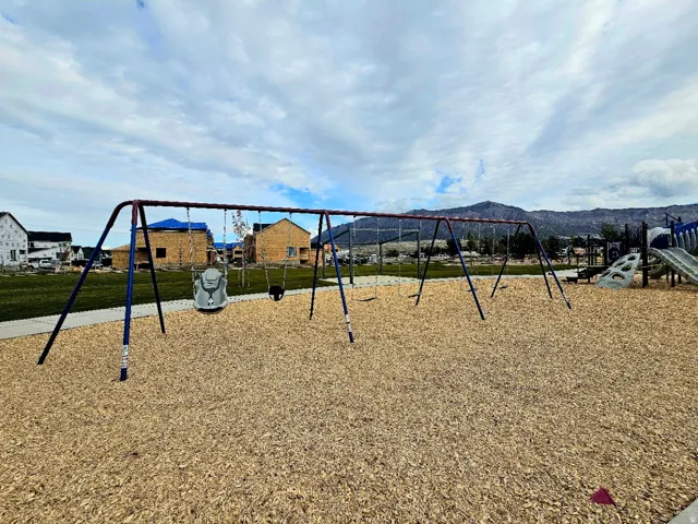Community playground featuring swings, wood chip ground cover, and adjacent play structures