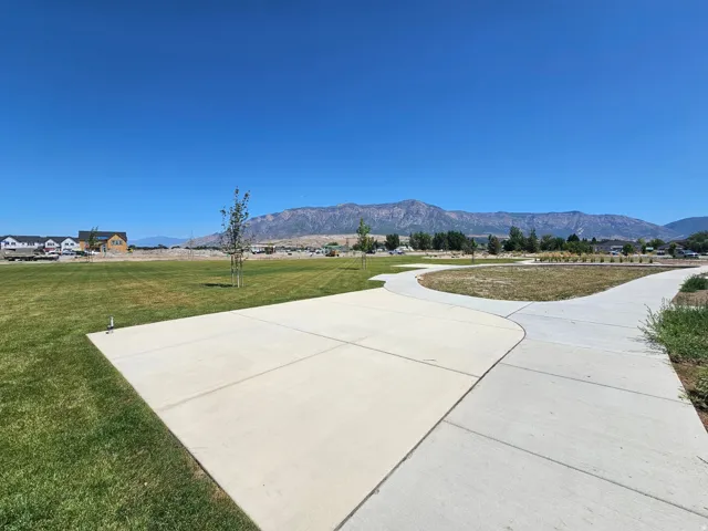 Expansive green space featuring concrete pathways and mountain backdrop