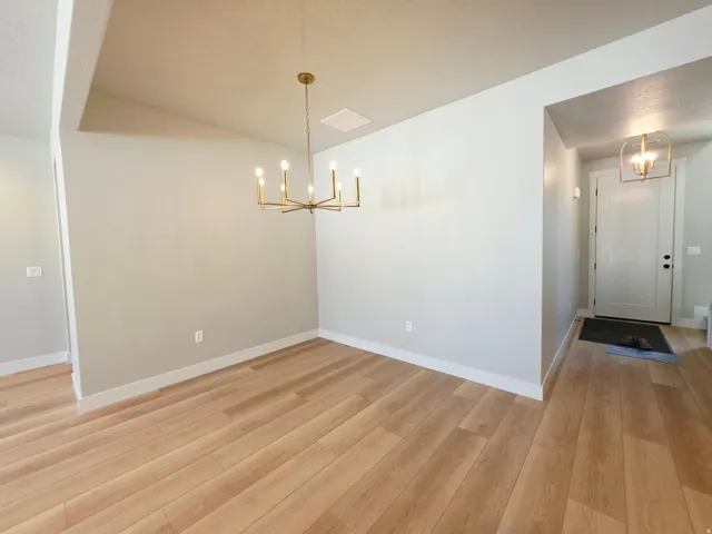 Wood-finish flooring, vaulted ceiling, brass chandelier, recessed lighting, and white interior doors