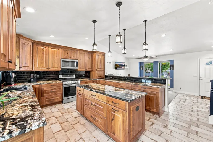 Expansive kitchen featuring warm wood cabinetry, granite countertops, and a large center island with prep space
