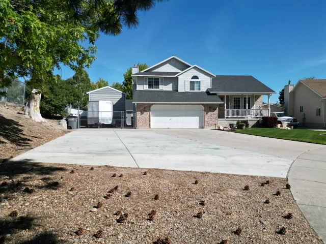 Two-story exterior with brick and siding facade, covered front porch, attached two-car garage, and expansive concrete driveway