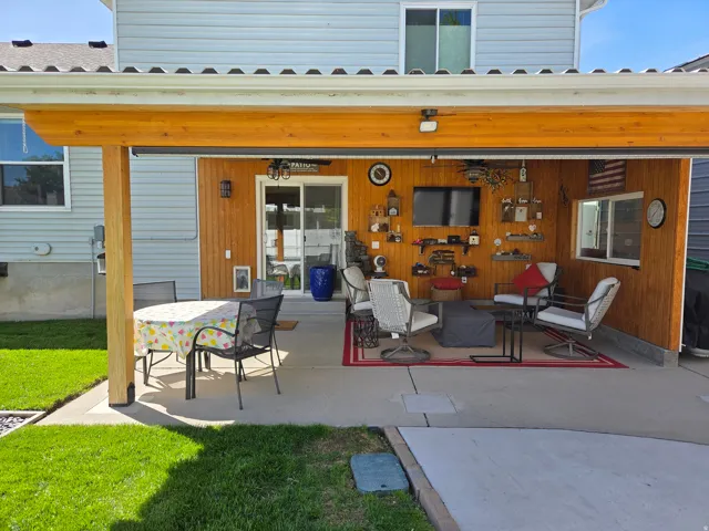 Covered patio with a concrete surface, wood-paneled accent wall, and sliding glass door access