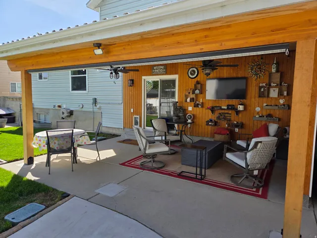 Covered patio area featuring a slatted wood accent wall, wood-finish ceiling, and concrete flooring