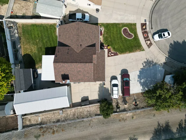 Good View of thr 14' x16' x 40' Covered Rv Pad, expansive concrete driveway, manicured front lawn with decorative rock features, mature tree landscaping, and outbuildings
