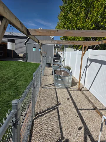 white privacy fencing, gravel pathway, and raised garden bed