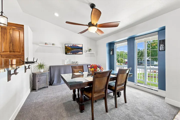 Vaulted ceiling with a ceiling fan, carpeted flooring, built-in shelving, two large windows, and a built-in breakfast bar