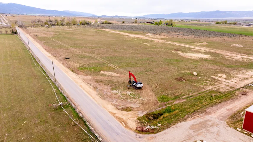 Expansive rural property featuring an unpaved road and distant mountain range