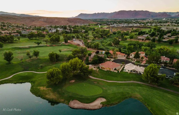 Golf course community with mountain scenery, mature trees, a water feature, and paved cart paths