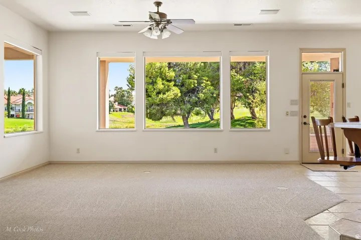 Expansive room featuring multiple windows, a ceiling fan, and a light-colored carpeted area