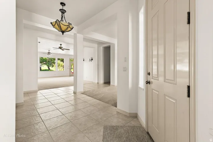 Recessed entry with tile flooring, an ornamental chandelier, and a paneled entry door