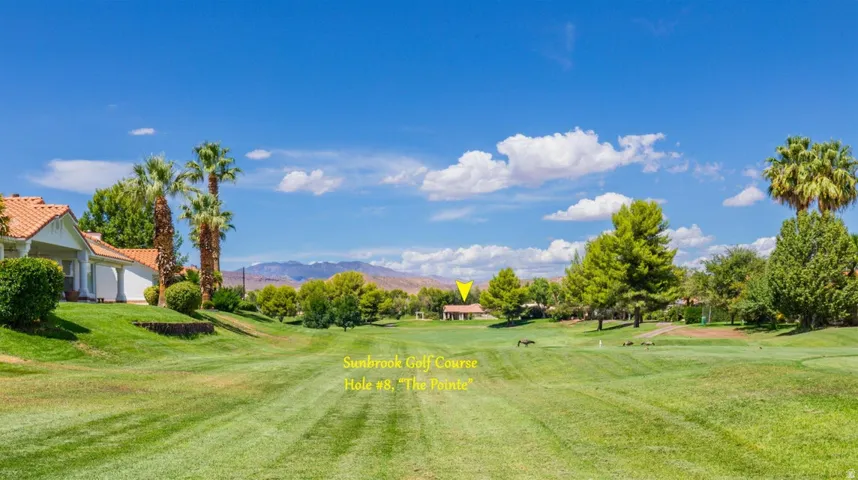 Expansive green space featuring a golf course, mature trees, and distant mountains