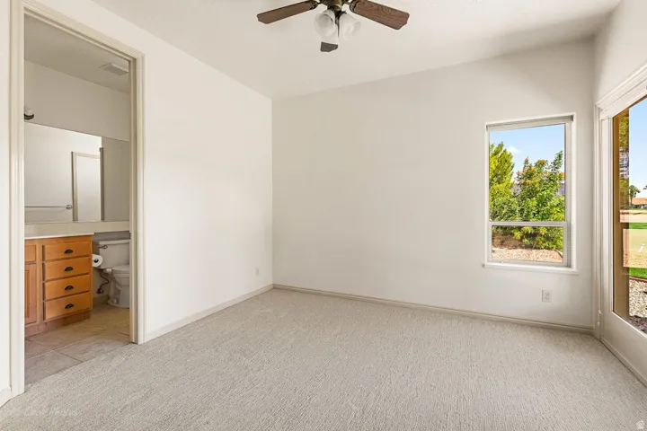 Carpeted room with a vaulted ceiling and ceiling fan