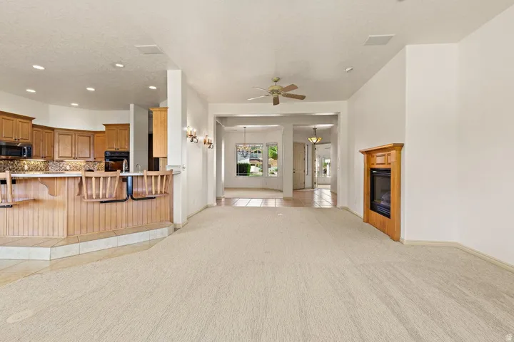 Built-in wood cabinetry, integrated kitchen appliances, ceiling fan, and corner fireplace with wood mantle