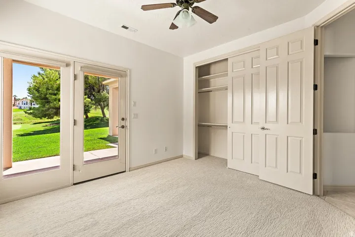 Double-door exterior access, built-in bi-fold closet, ceiling fan, and carpet flooring