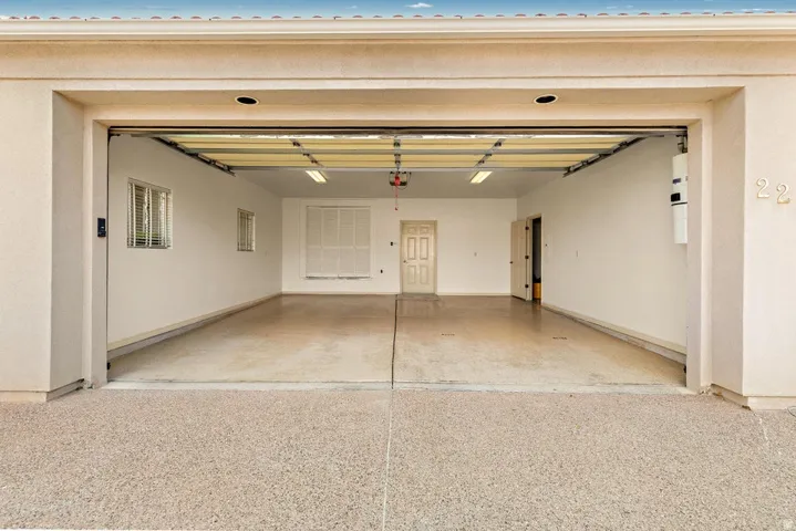 Spacious garage featuring a finished floor, multiple windows with blinds, and white panel doors