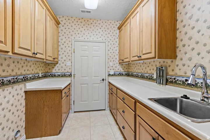 Extended countertop space, ample cabinetry, stainless steel sink, and tile flooring