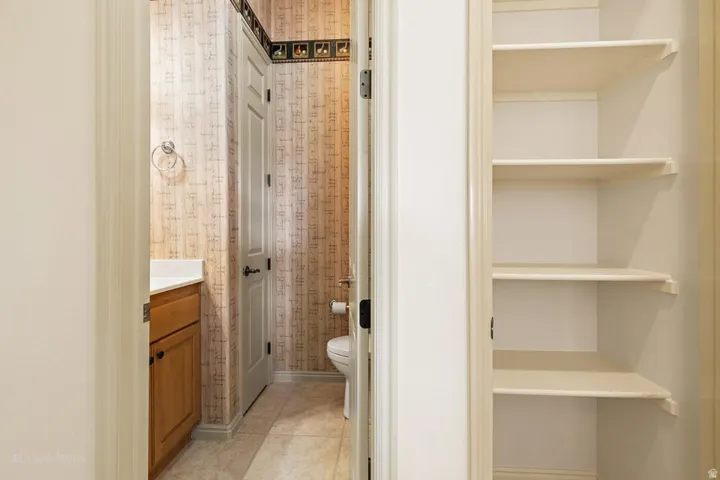 Built-in shelving, wood-finish vanity with countertop, and floor tiling