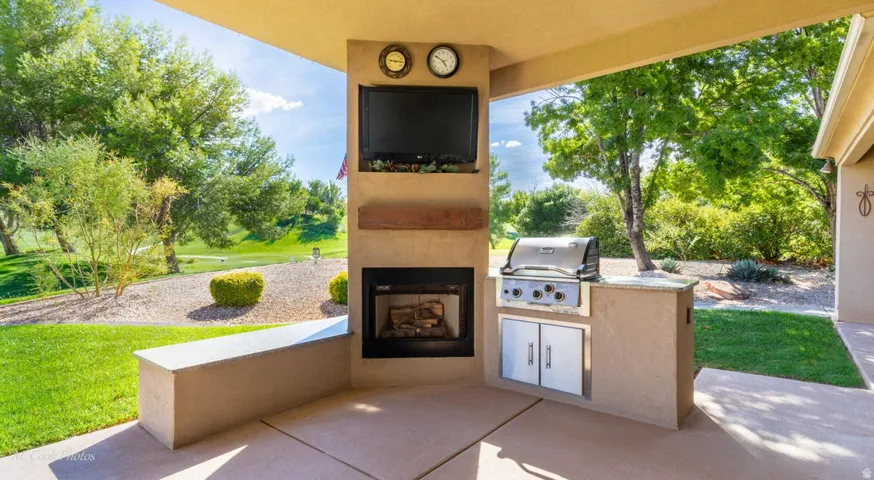 Covered patio with an outdoor fireplace, built-in television, built-in grill, and outdoor countertop