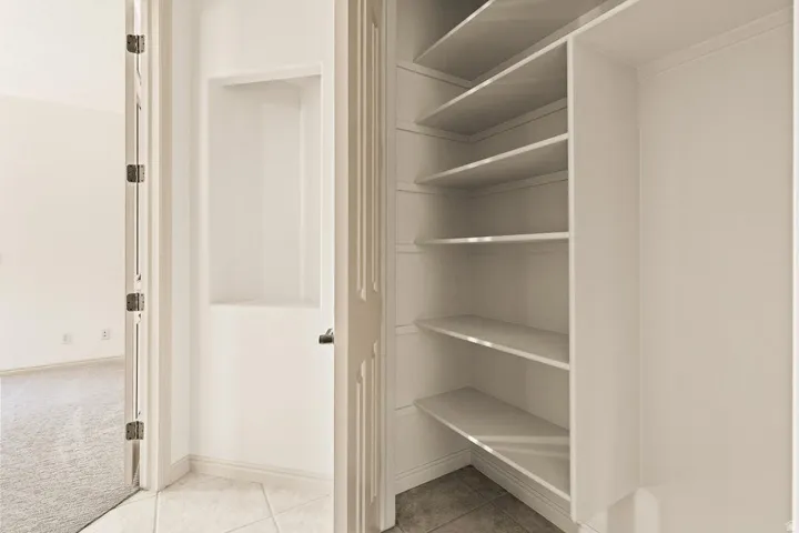 Built-in shelving, recessed wall niche, tiled flooring, wood-paneled door