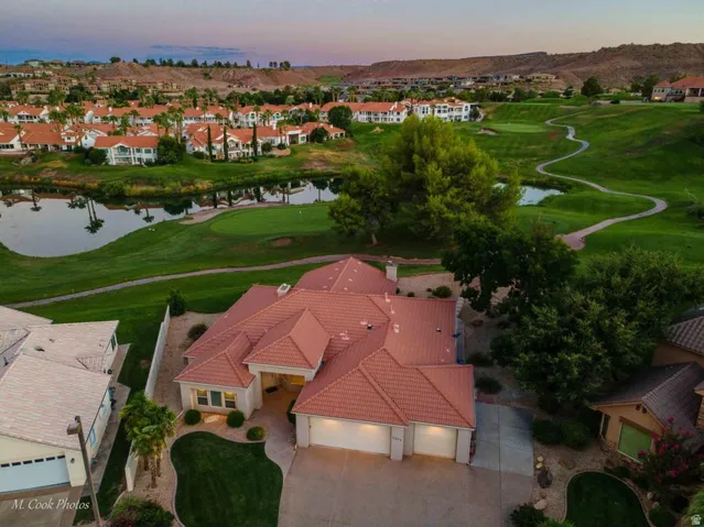 Terracotta tile roof, attached two-car garage, manicured front lawn, and mature landscaping