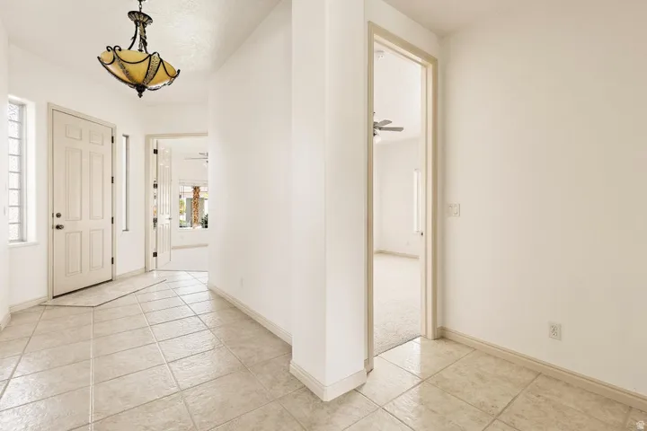Tiled entryway with a decorative overhead light fixture, paneled doors, and natural light from frosted windows