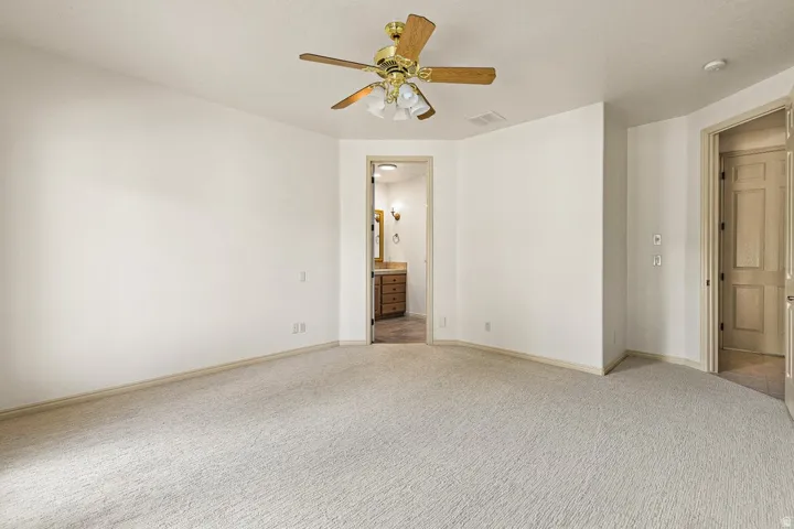 Neutral tone carpet flooring with a ceiling fan light fixture