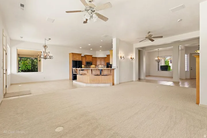 Expansive open-concept living area featuring a kitchen with wood cabinetry, a breakfast bar, and black appliances
