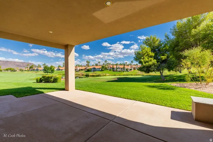 Covered patio with recessed lighting, offering an expansive lawn area and distant mountain backdrop