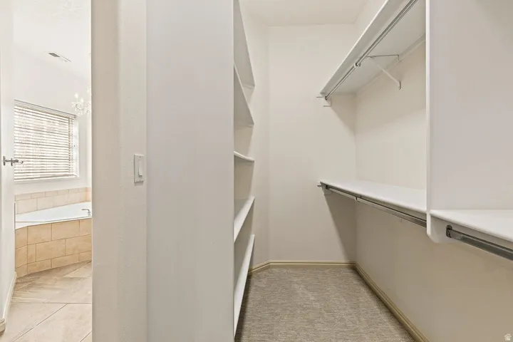Walk-in closet with carpet flooring, integrated shelving, and hanging rods