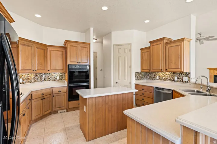 Kitchen featuring extensive wood cabinetry, light-toned countertops, tile flooring, and a mosaic tile backsplash