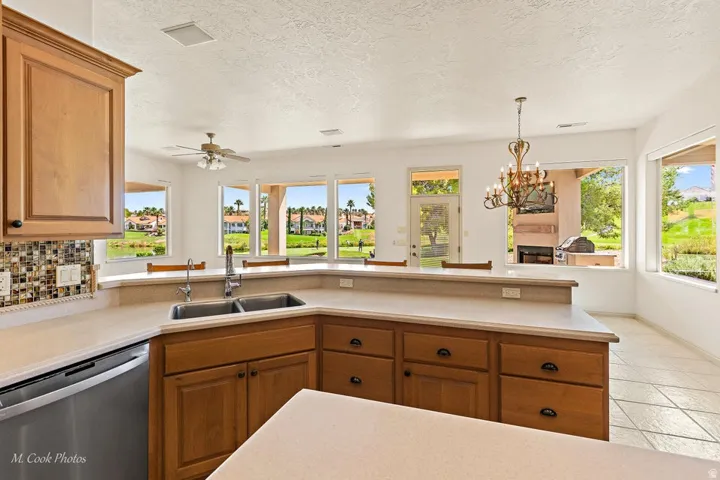 Kitchen featuring wood-finish cabinetry, a double basin sink, and mosaic tile backsplash