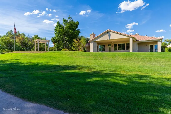 Expansive green lawn sloping towards a stucco exterior with a terra cotta tile roof