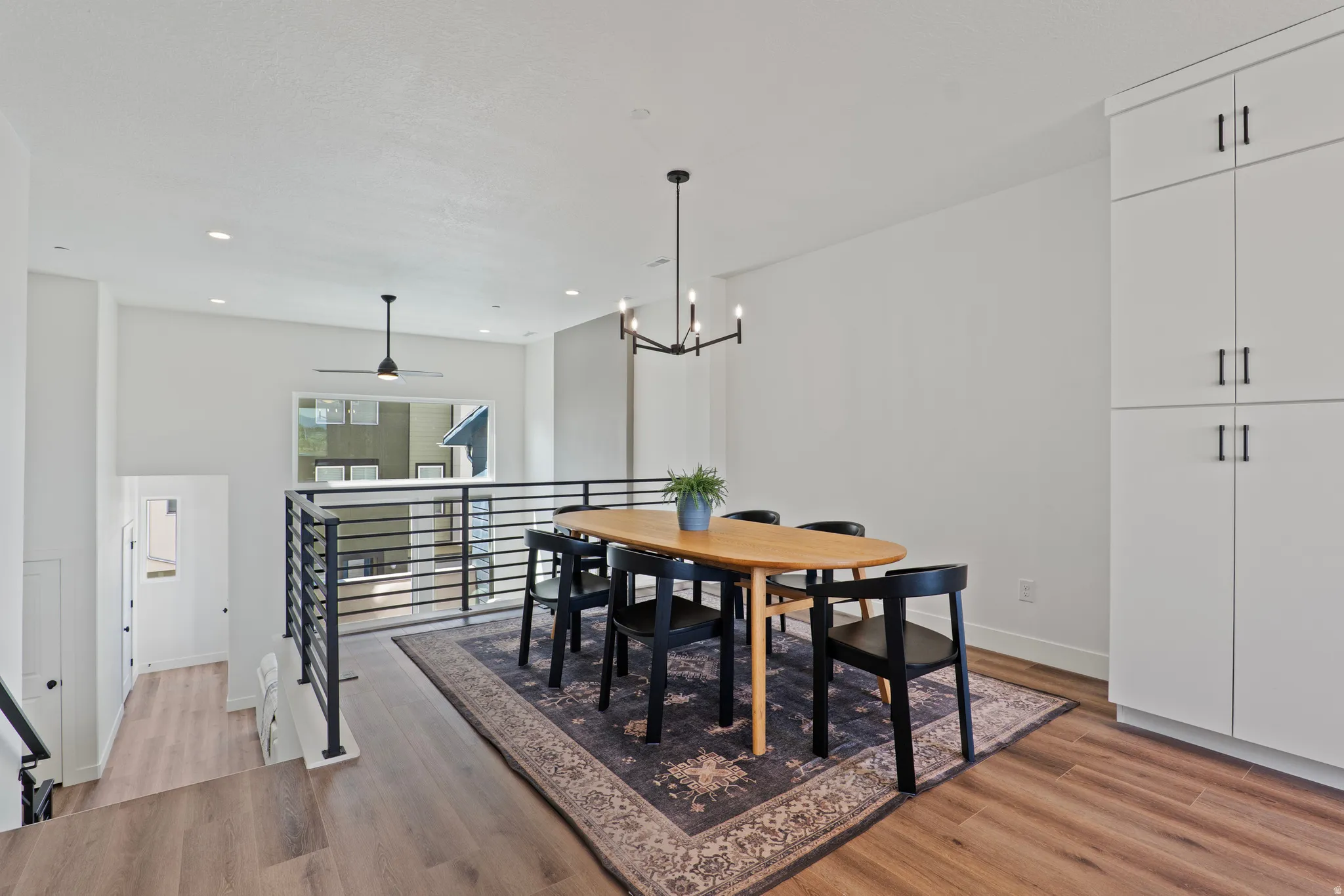 Open-concept dining area featuring wood-finish flooring, recessed lighting, and a modern chandelier