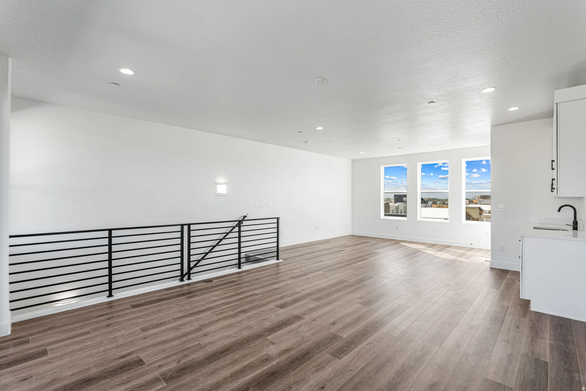 Open-concept living space featuring wood-finish flooring, recessed lighting, and multiple windows