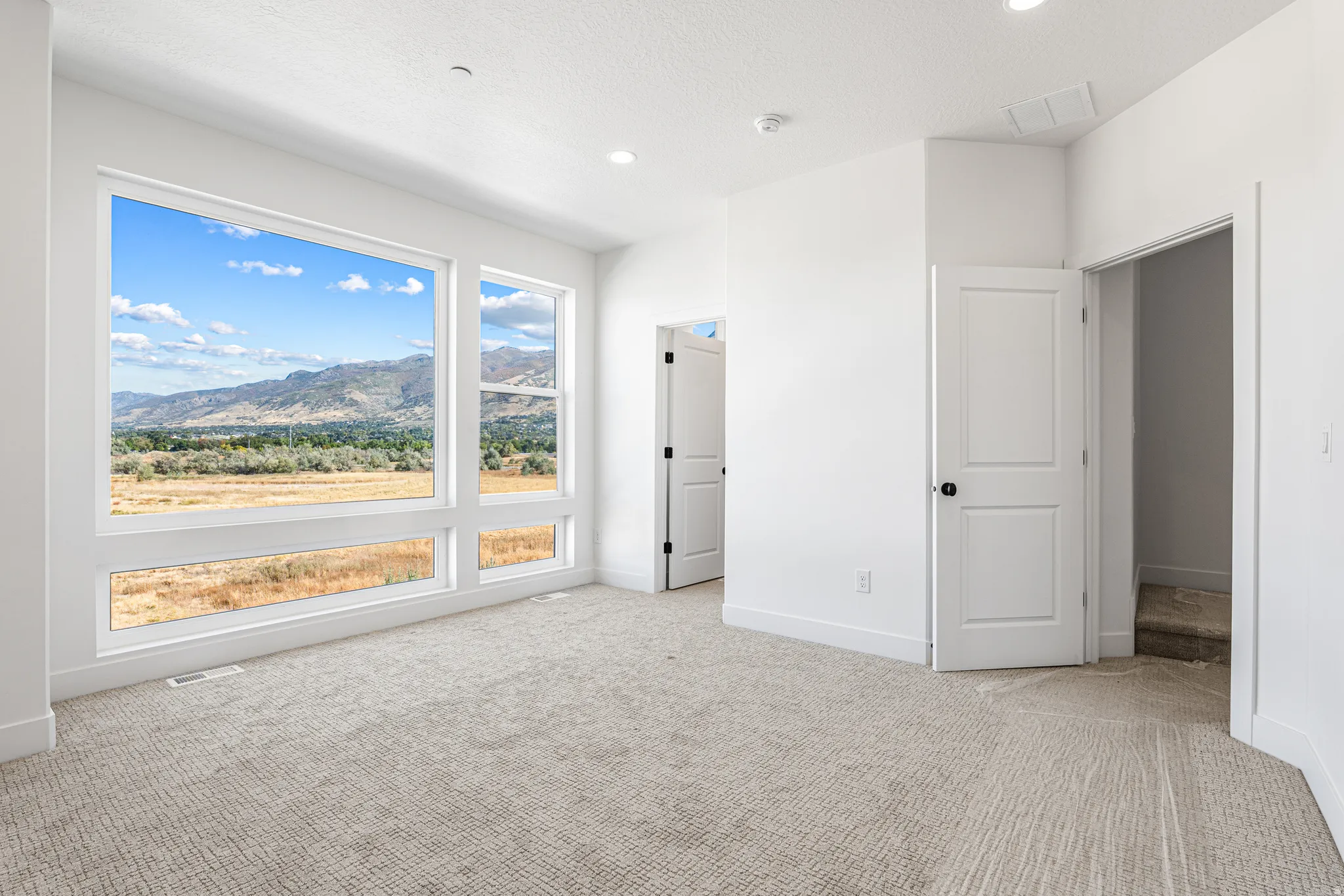 Expansive window wall with mountain backdrop, recessed ceiling lighting, and carpeted flooring